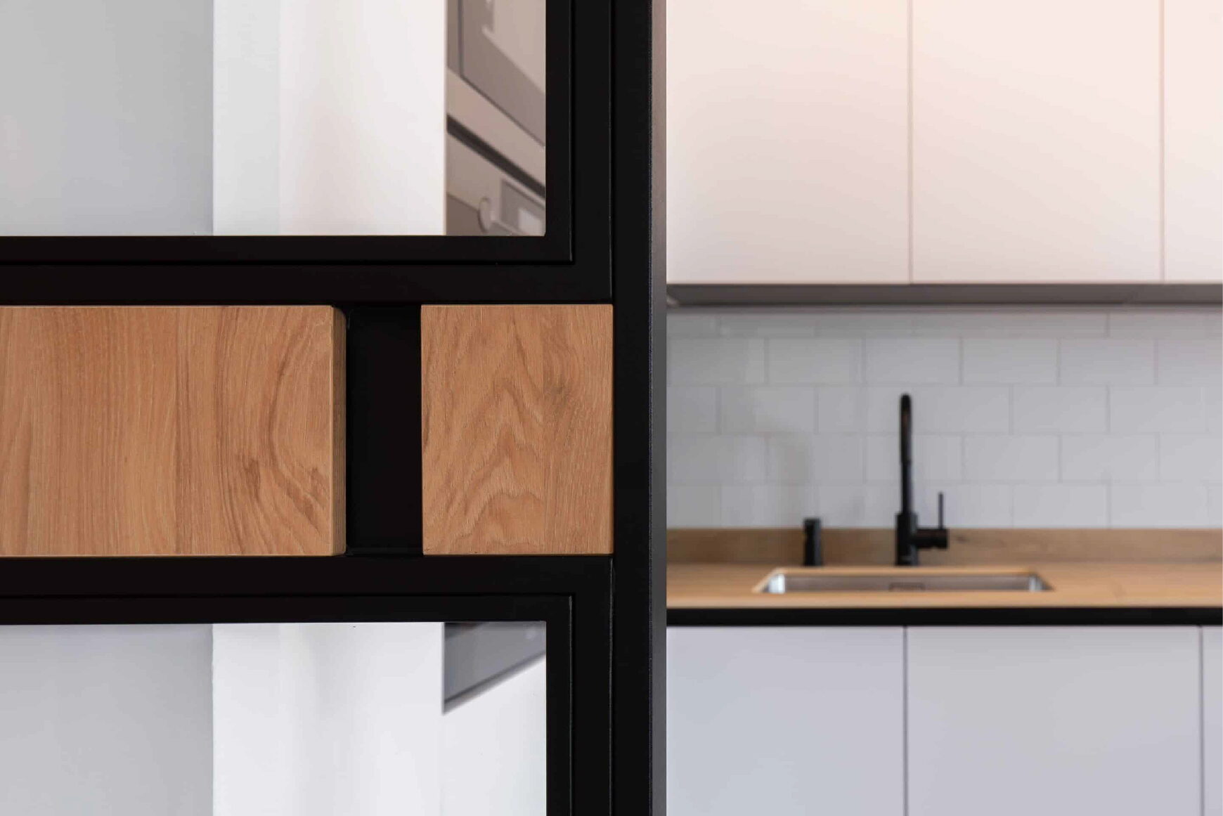 Detalle del cerramiento negro con piezas de madera junto a la cocina