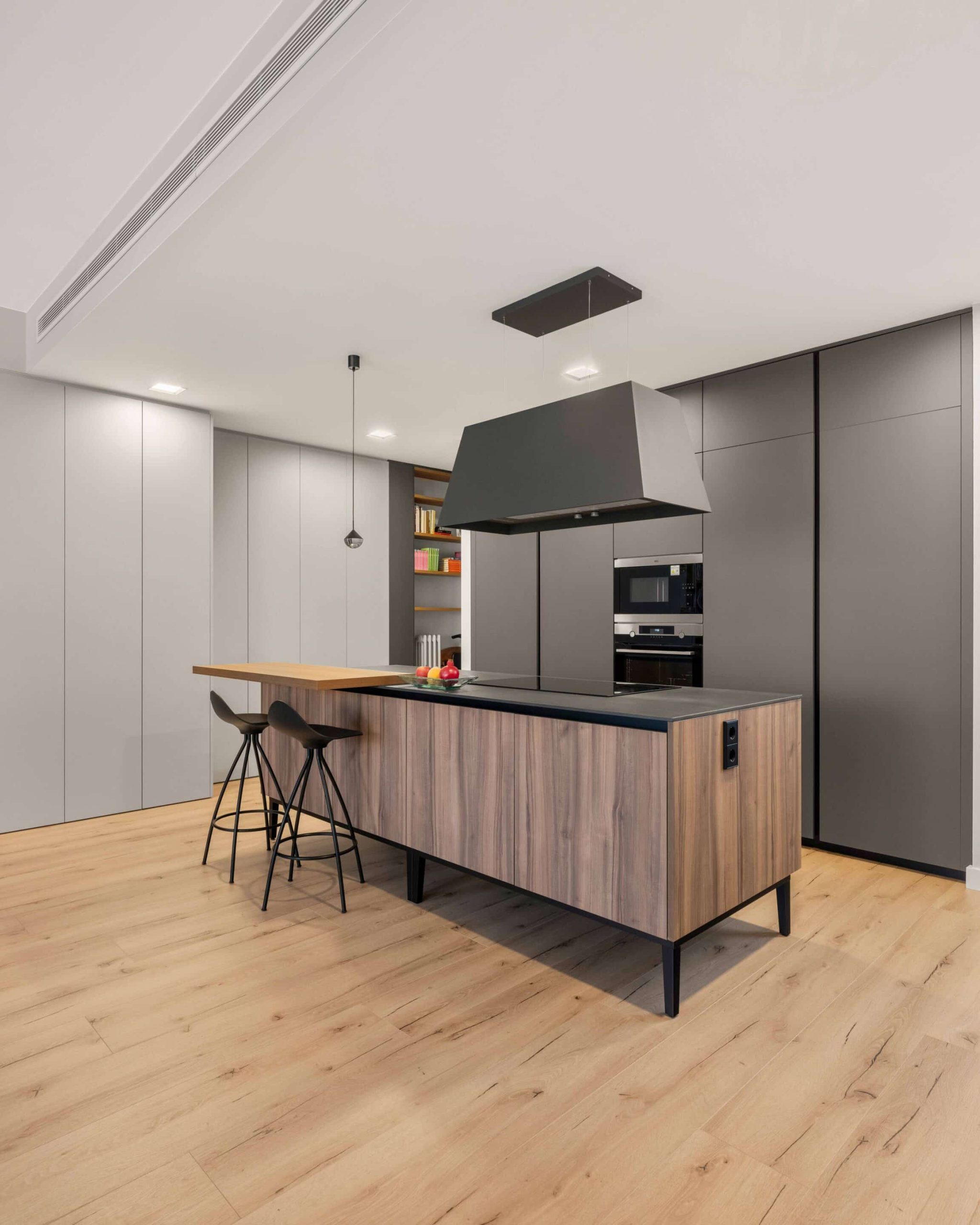 Cocina gris con isla y barra de desayuno en un piso reformado