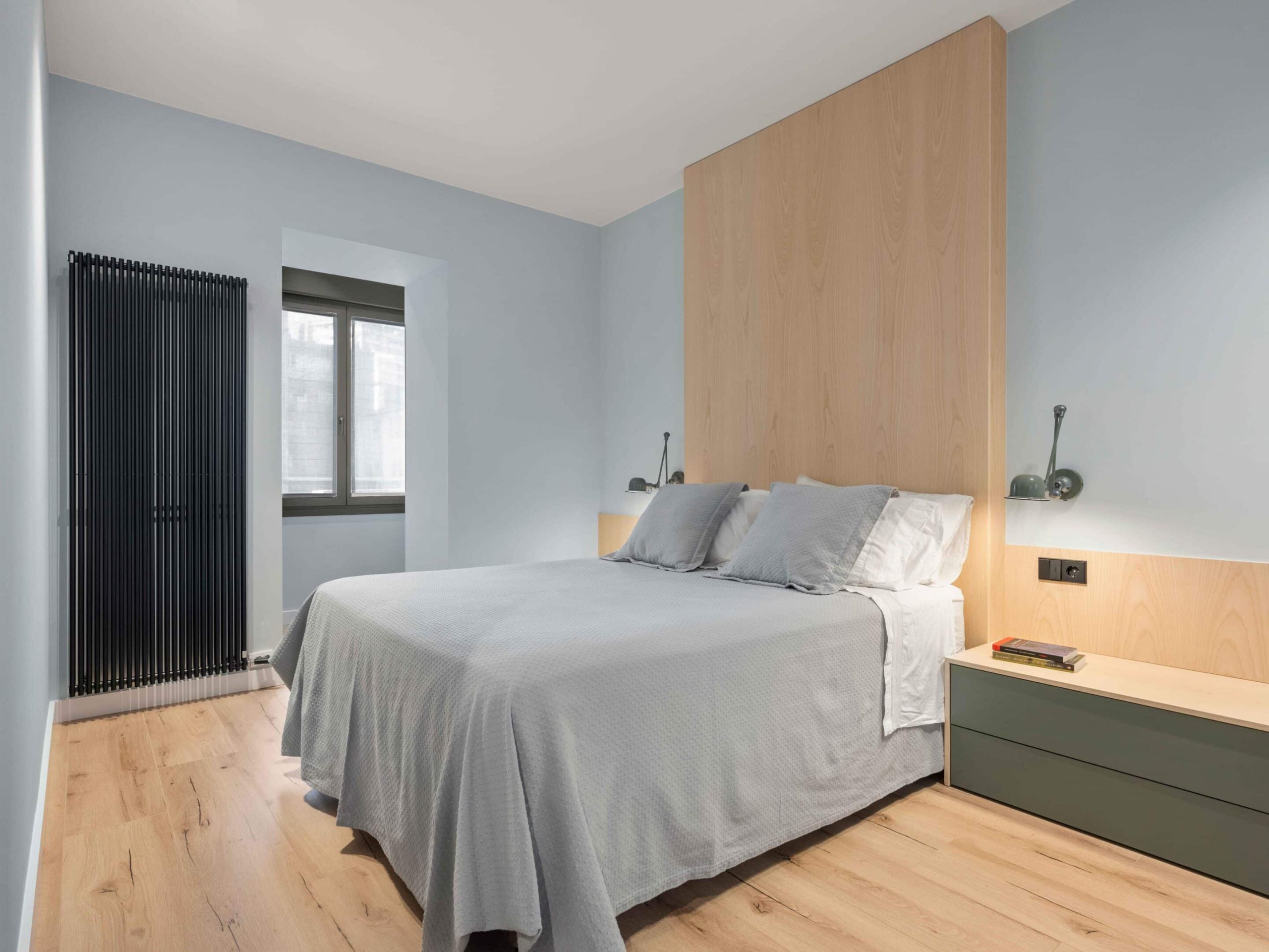 Dormitorio con cabecero de madera a techo y paredes azules