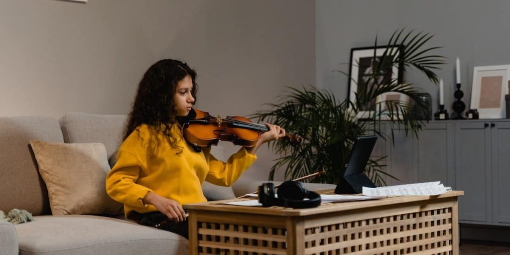 nina tocando el violin en sofa
