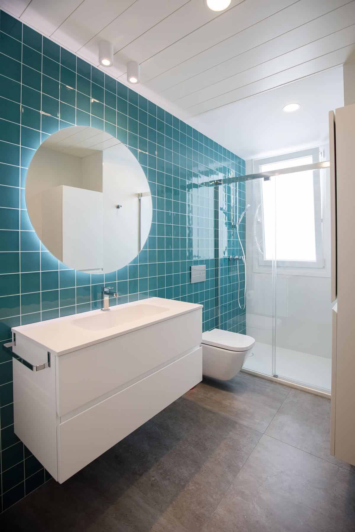 Baño con azulejo turquesa y espejo redondo, proyecto GV 11