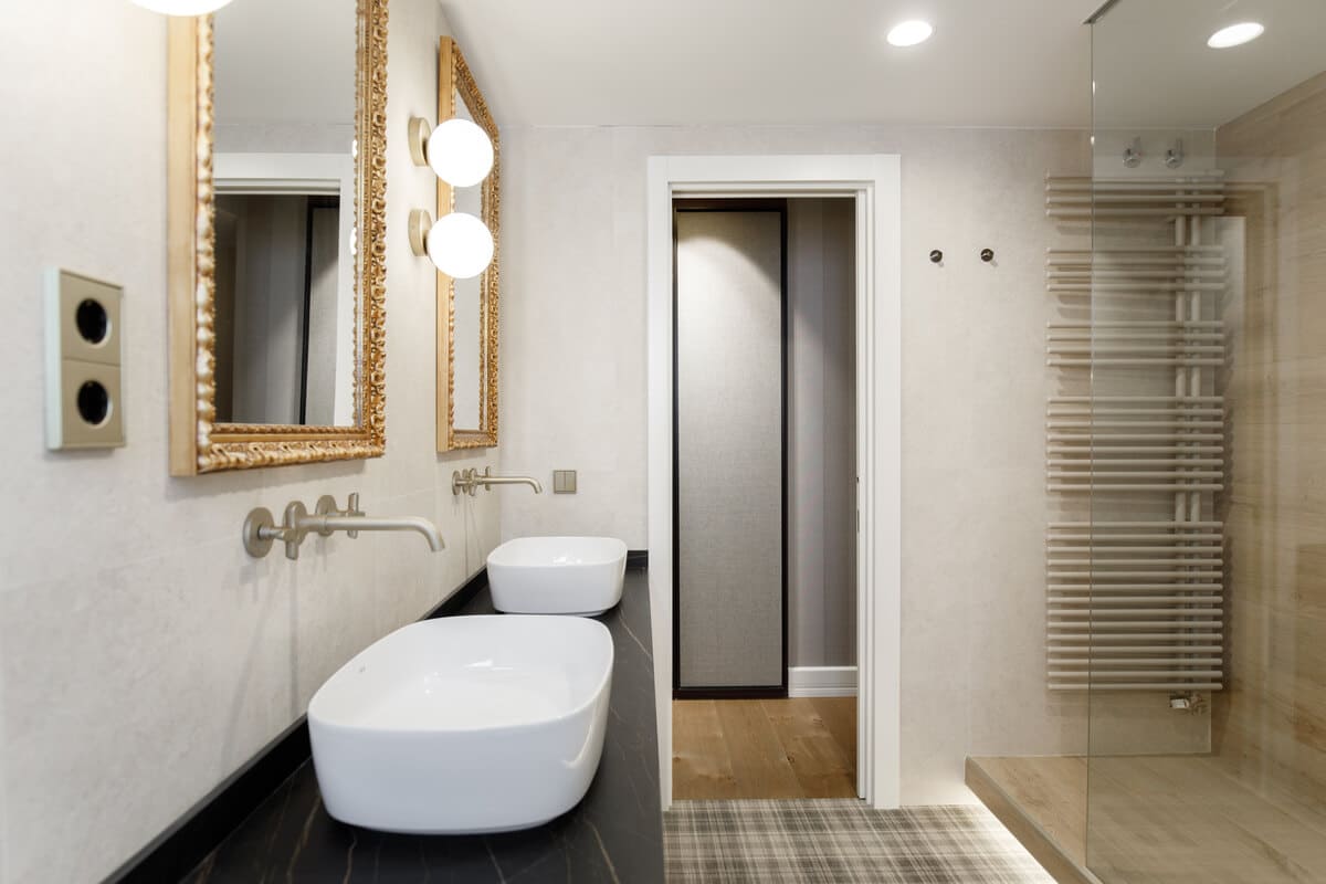 Baño con espejos de marco dorado y lavabo doble