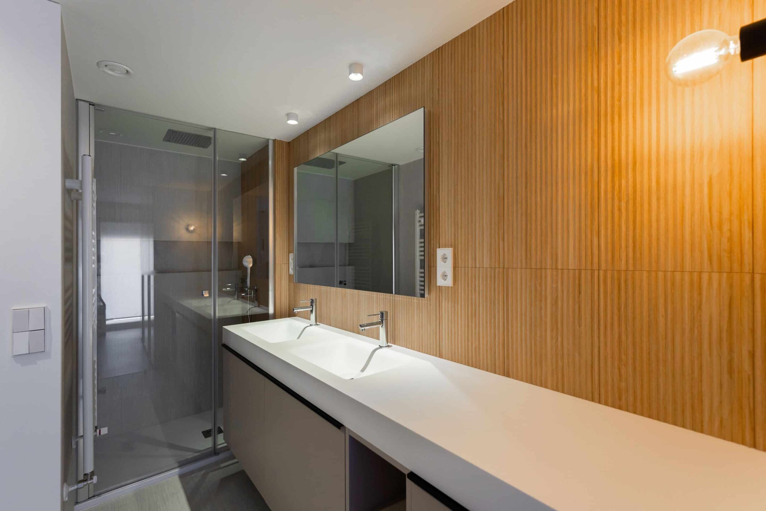 Baño con lavabo doble y pared de madera