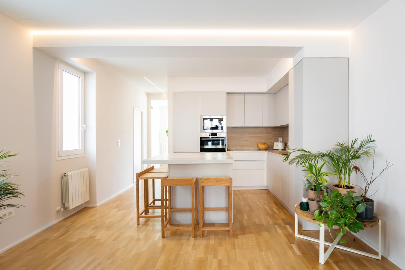 Cocina blanca con barra de madera y taburetes