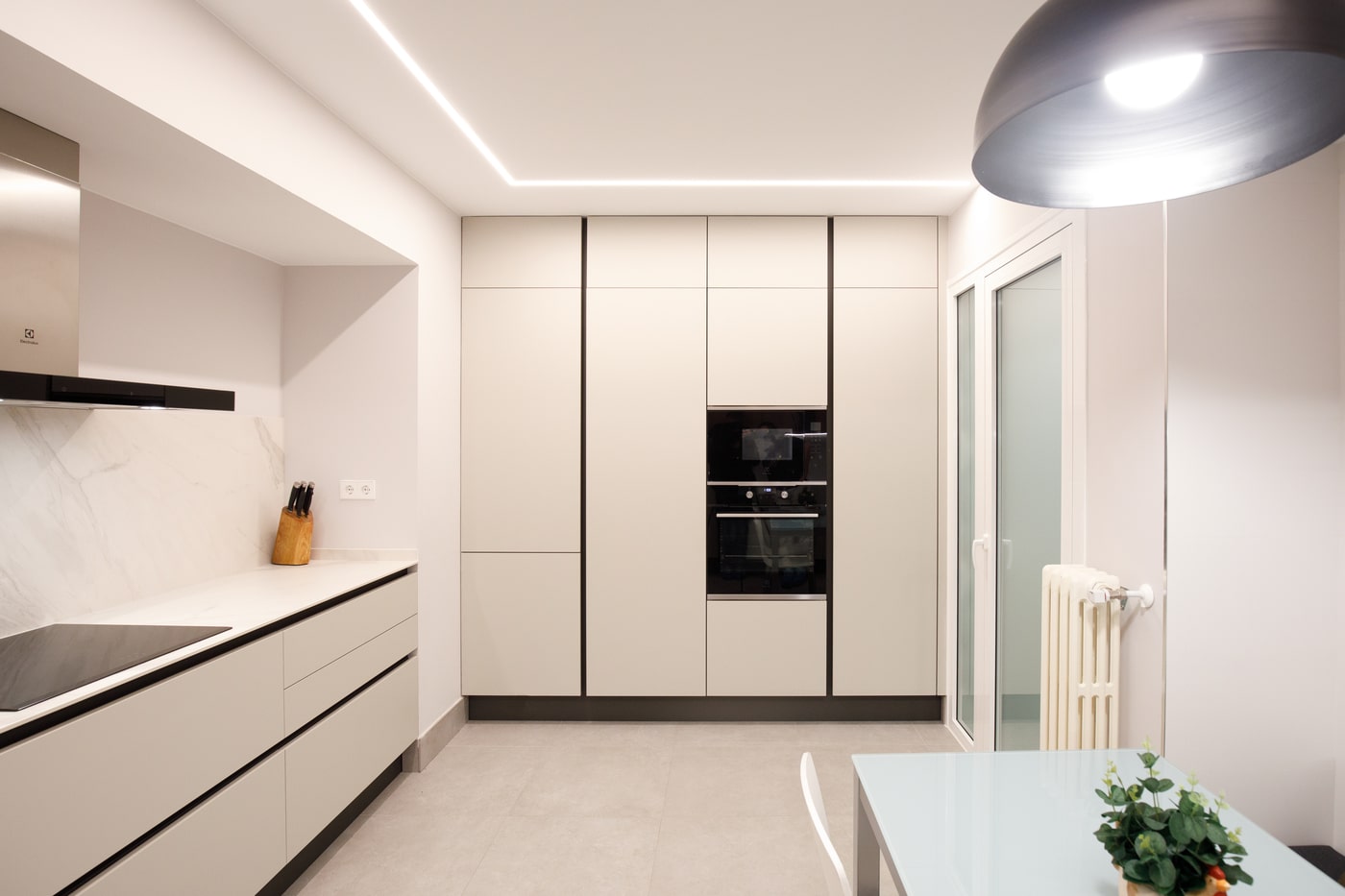 Cocina blanca con columnas y radiador de hierro