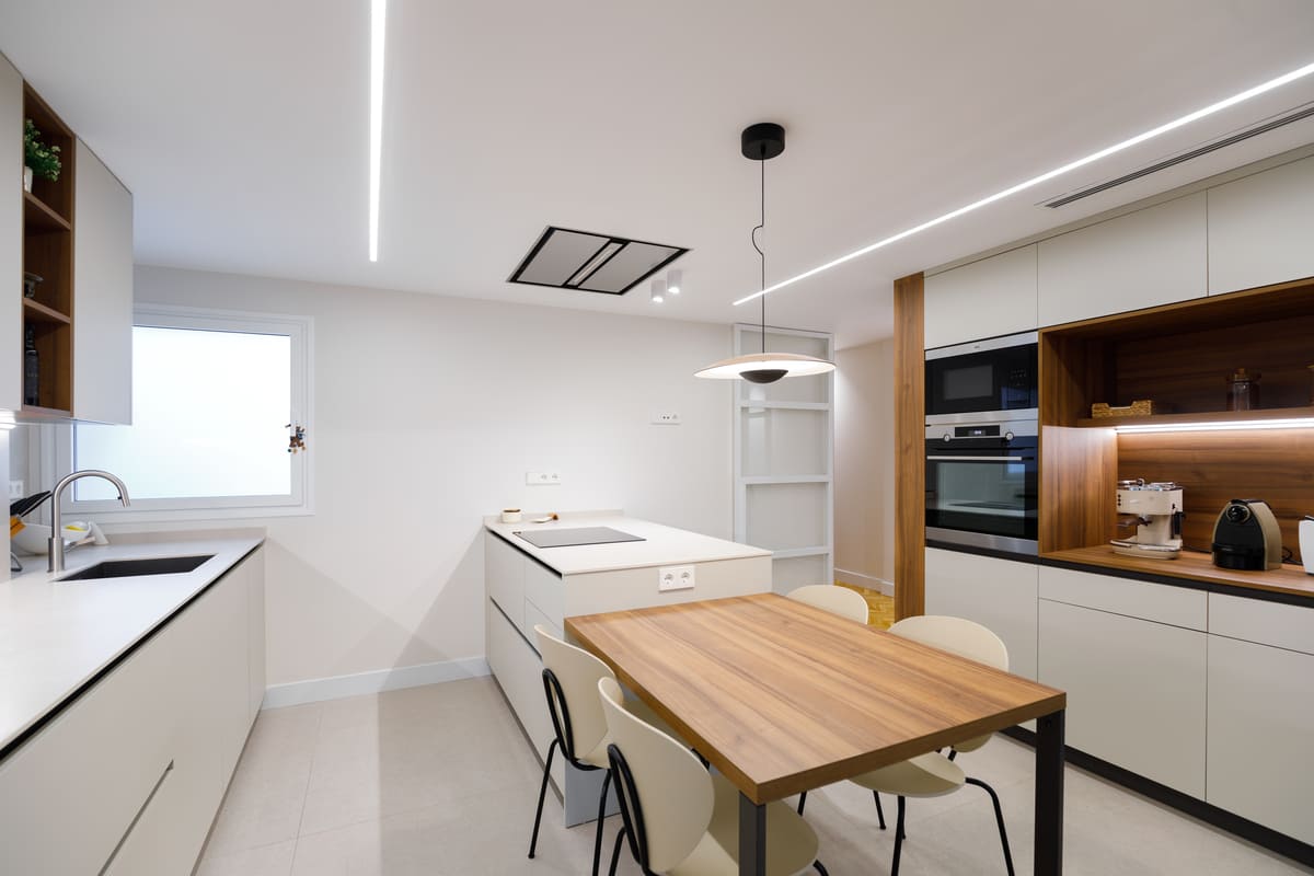 Cocina con mesa de madera integrada y columna de hornos