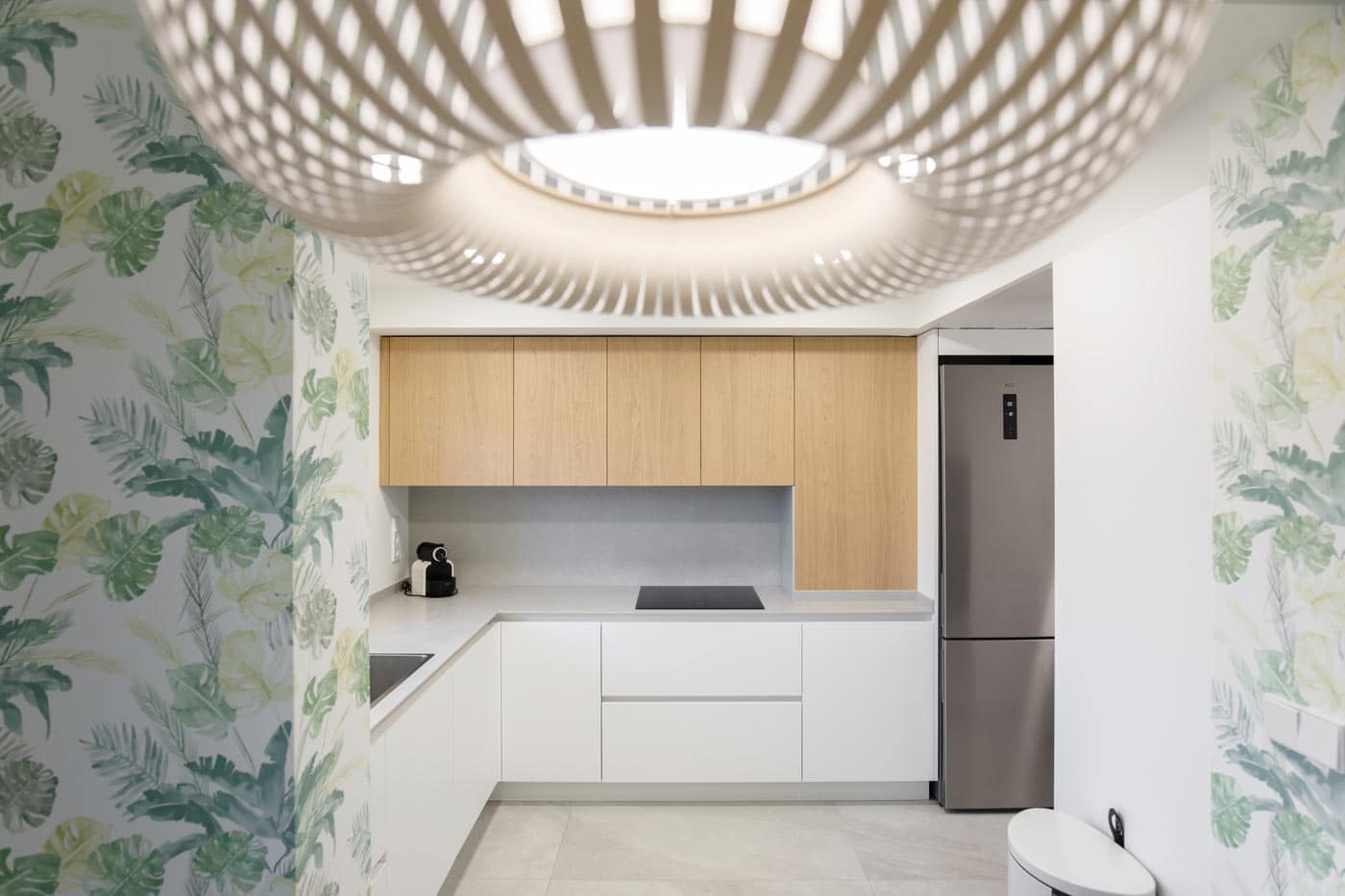Cocina con papel pintado tropical y lámpara de madera