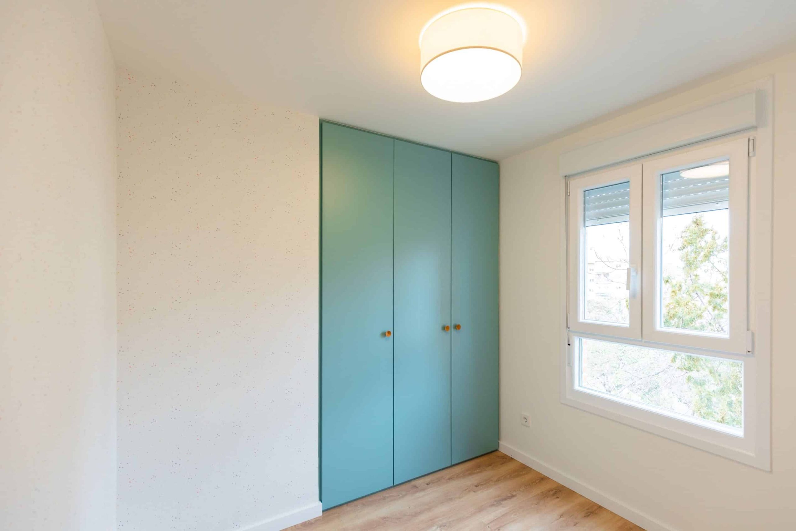 Dormitorio con armario turquesa en una vivienda reformada