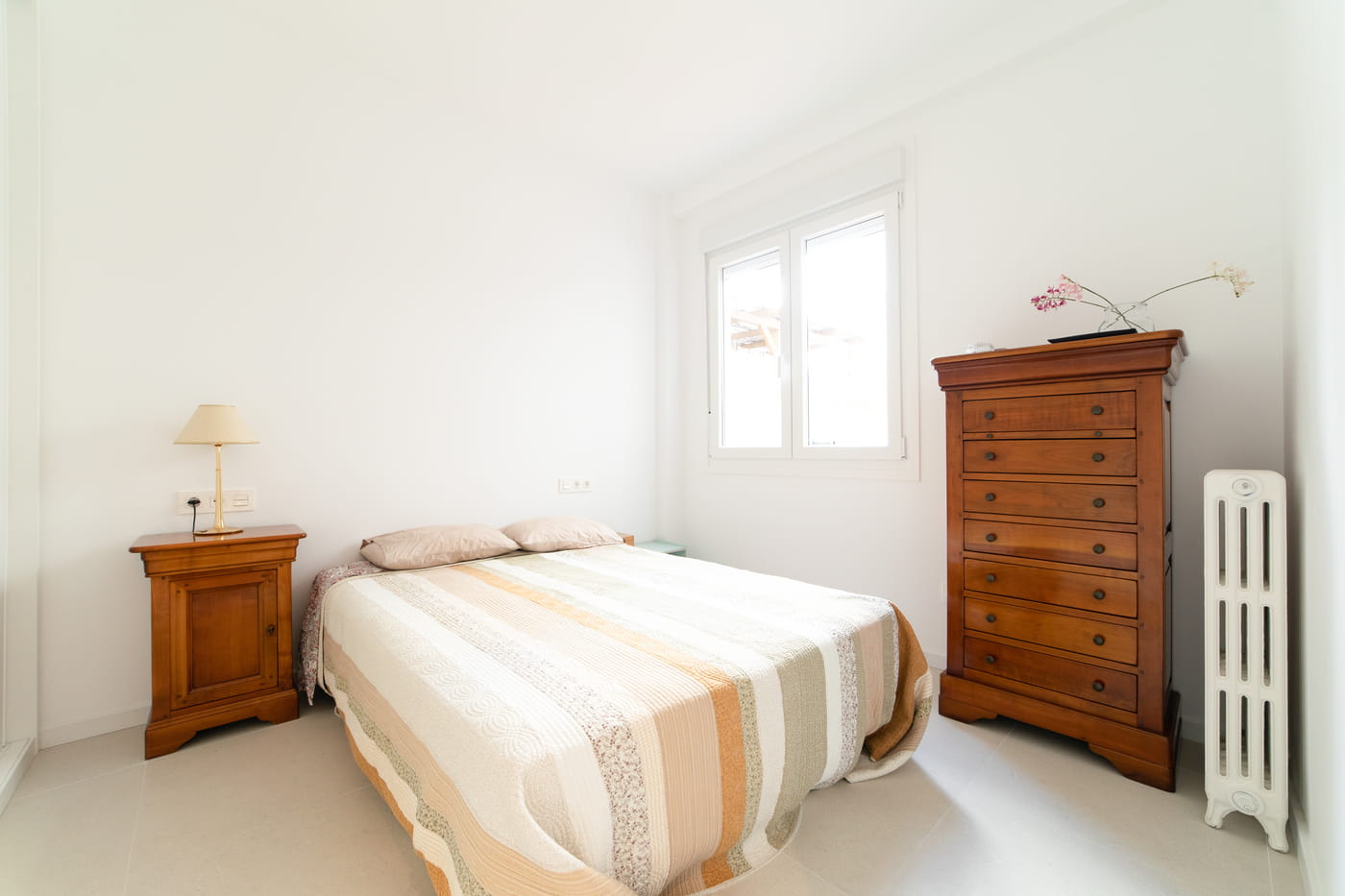 Dormitorio con cómoda antigua de madera en un piso reformado