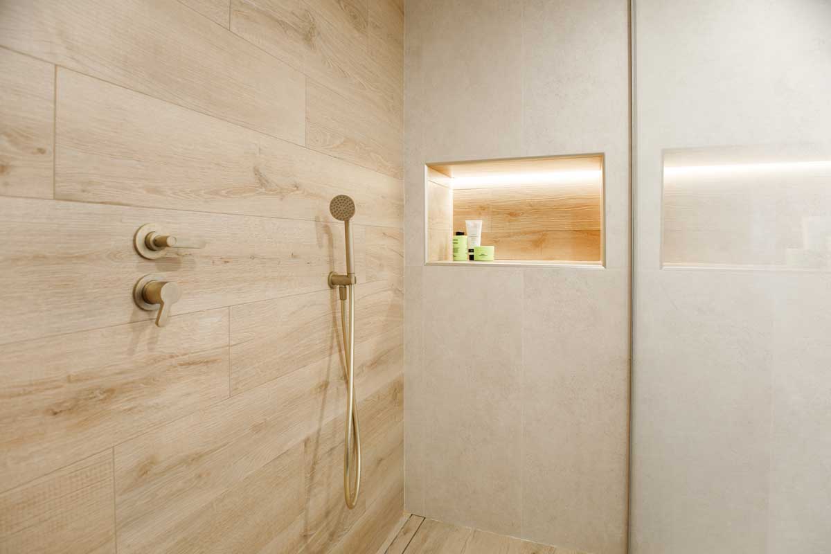 Ducha con porcelánico efecto madera y grifería dorada