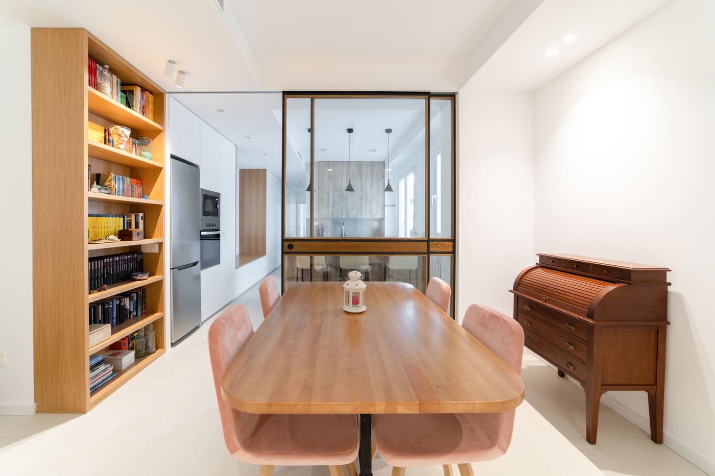 Mesa de comedor con sillas rosas y librería de madera
