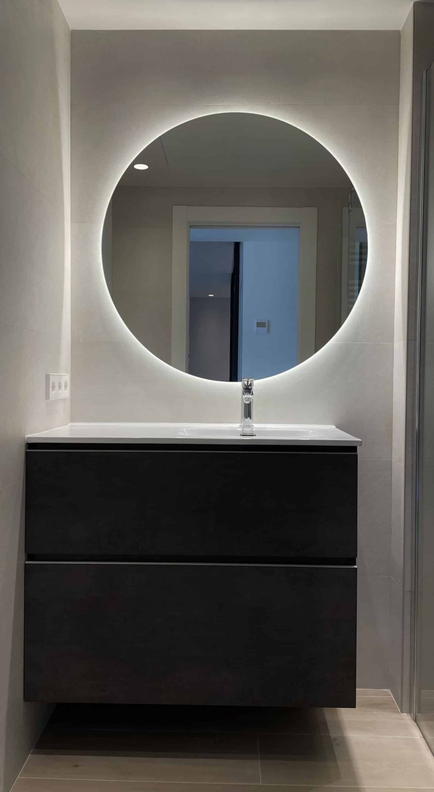 Mueble de baño negro y espejo redondo retroiluminado