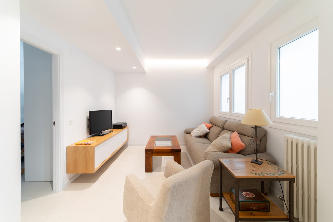 Salón blanco con sofá y mueble de televisión volado