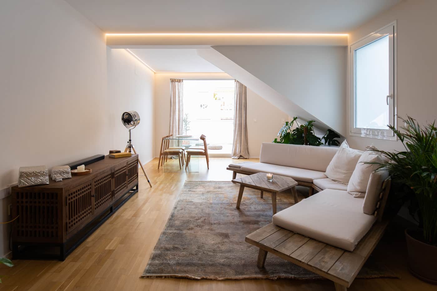 Salón en tonos blancos bajo la cubierta inclinada, proyecto JM 7