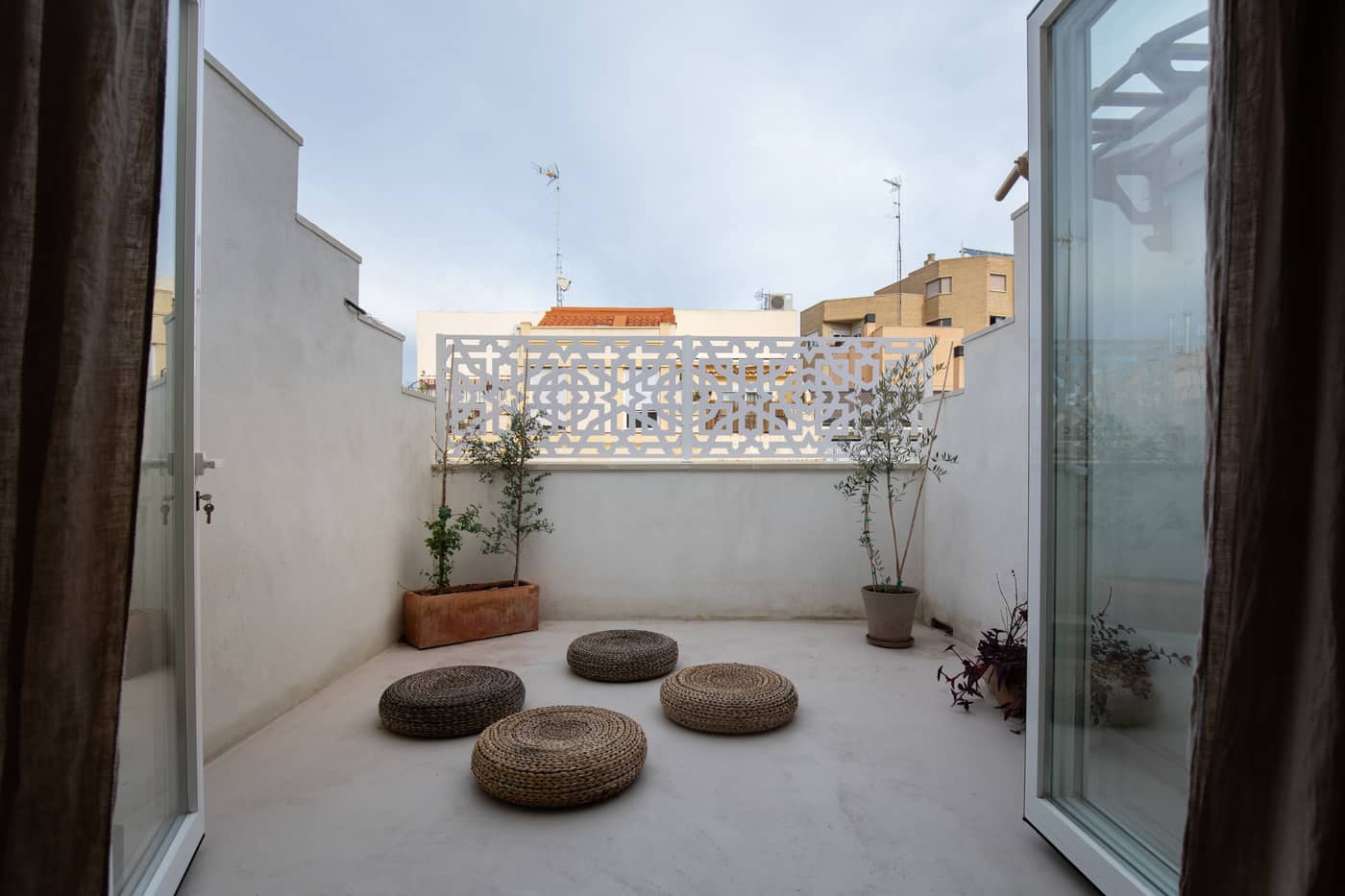 Terraza con celosía cerámica y puffs