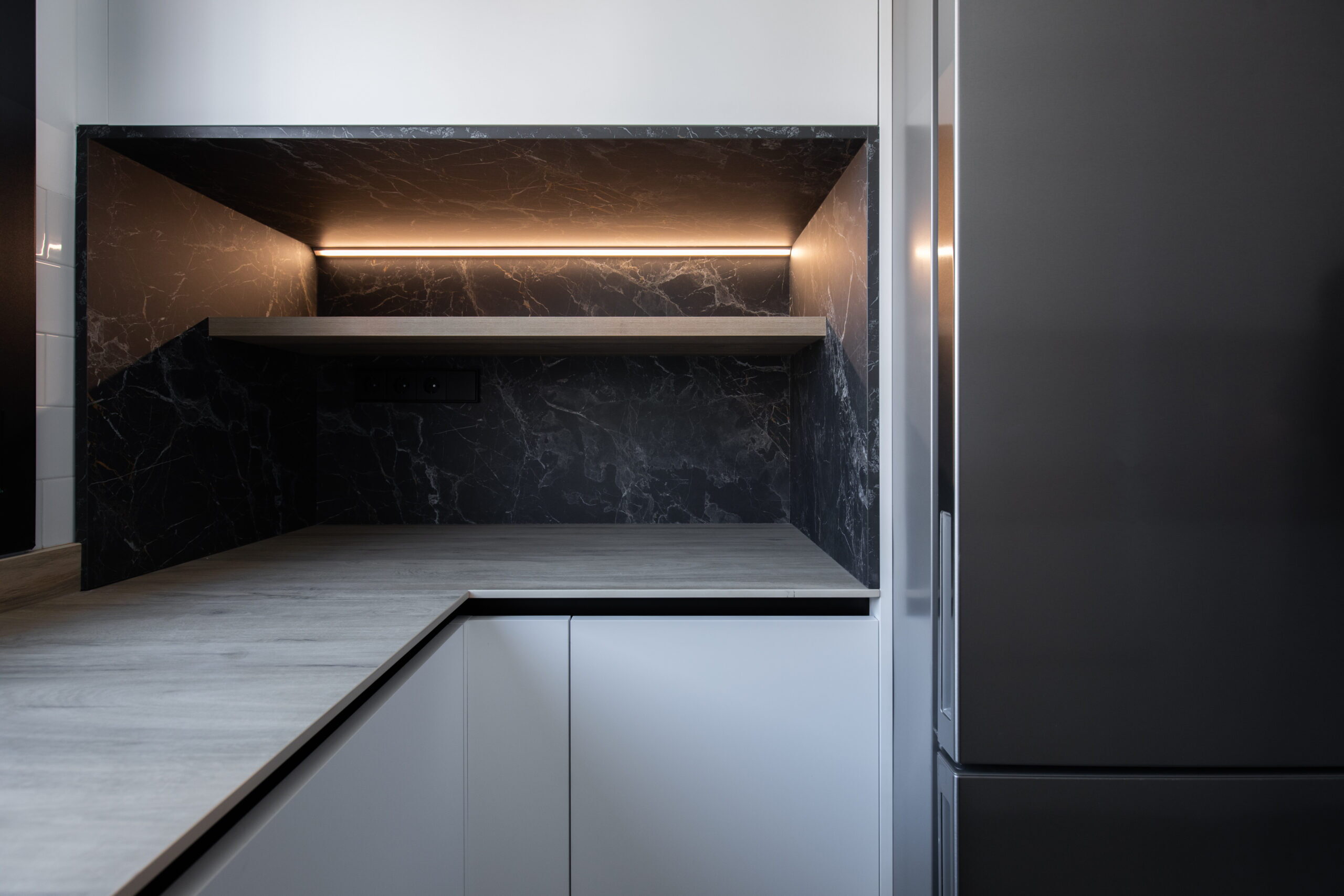 Rincón de cocina con estante iluminado y frente oscuro