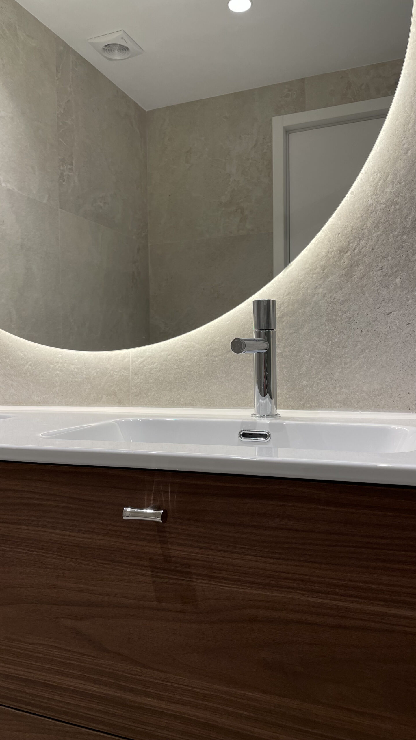 Lavabo con espejo redondo retroiluminado y mueble de nogal