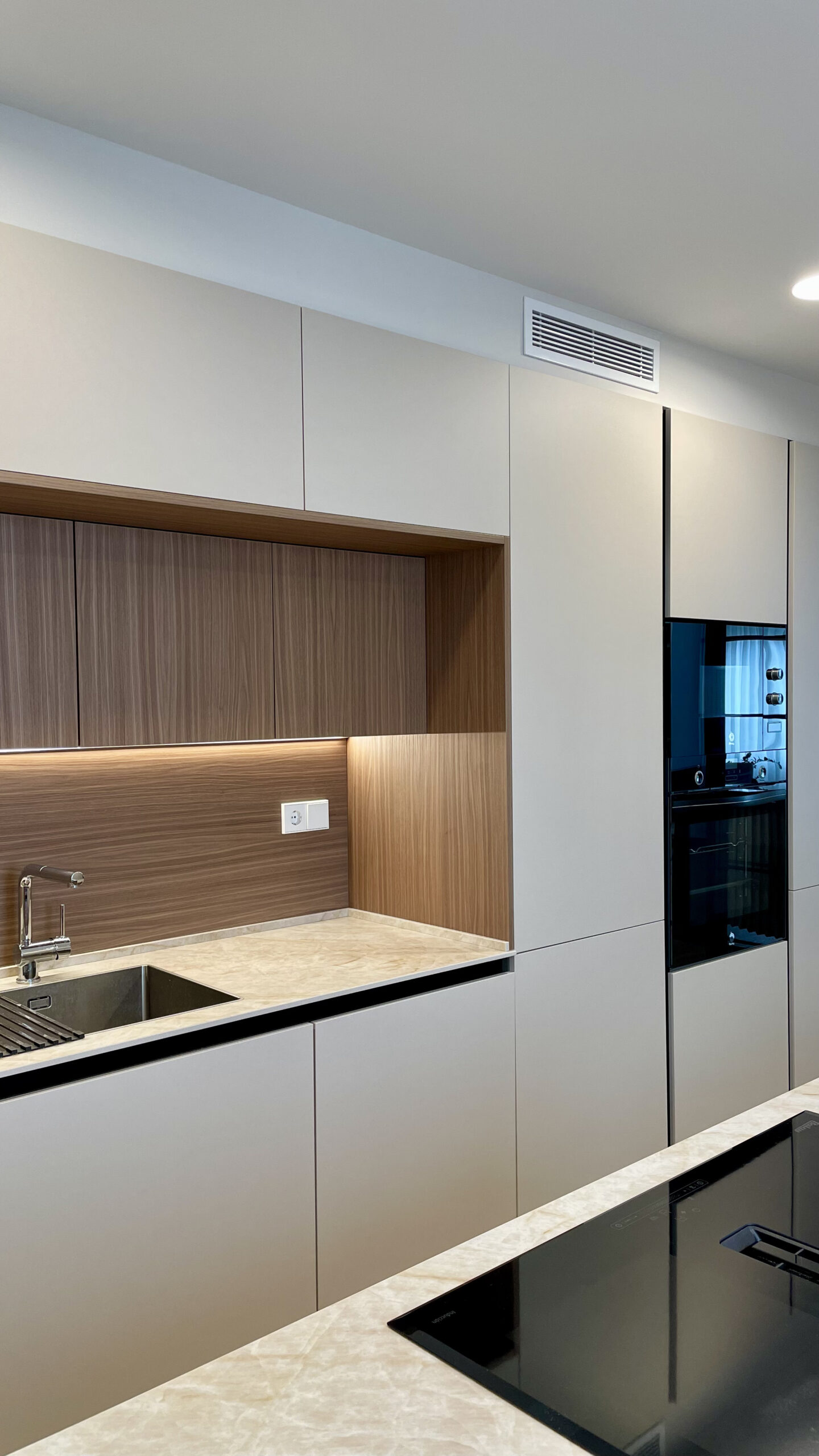 Cocina blanca con hueco de madera iluminado en una vivienda reformada