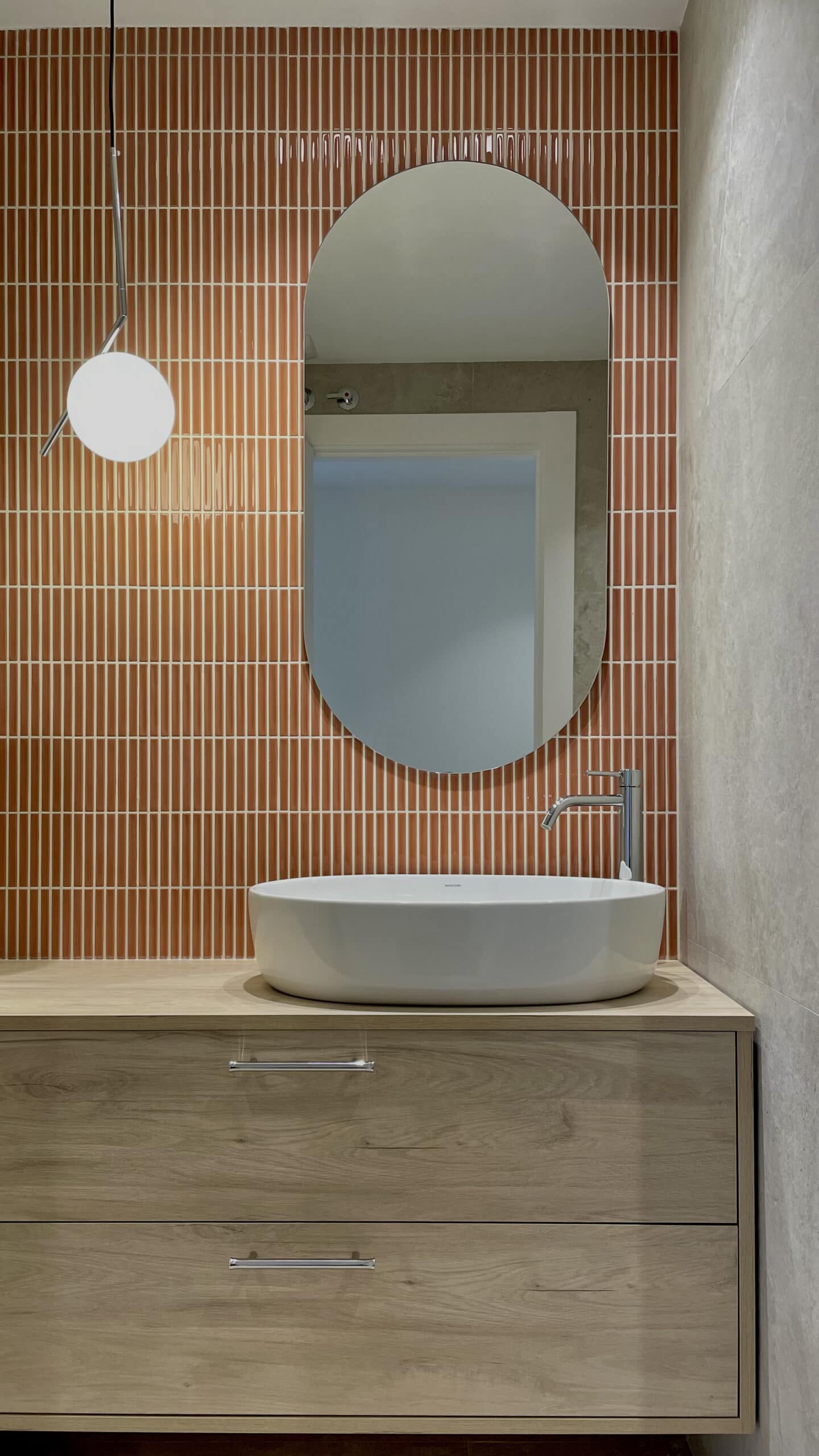 Baño con azulejo terracota y espejo ovalado