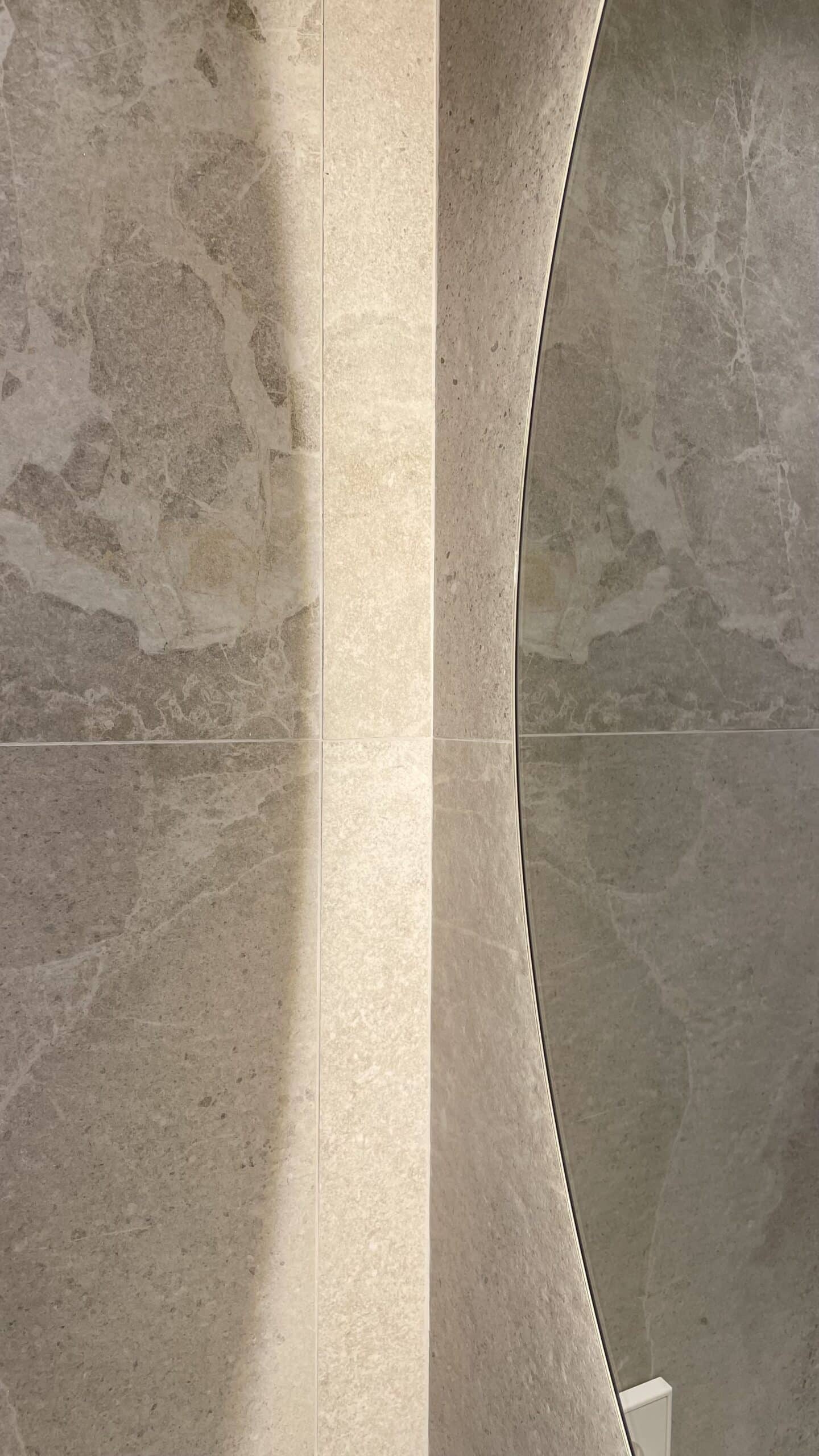 Detalle del espejo retroiluminado sobre porcelánico efecto piedra