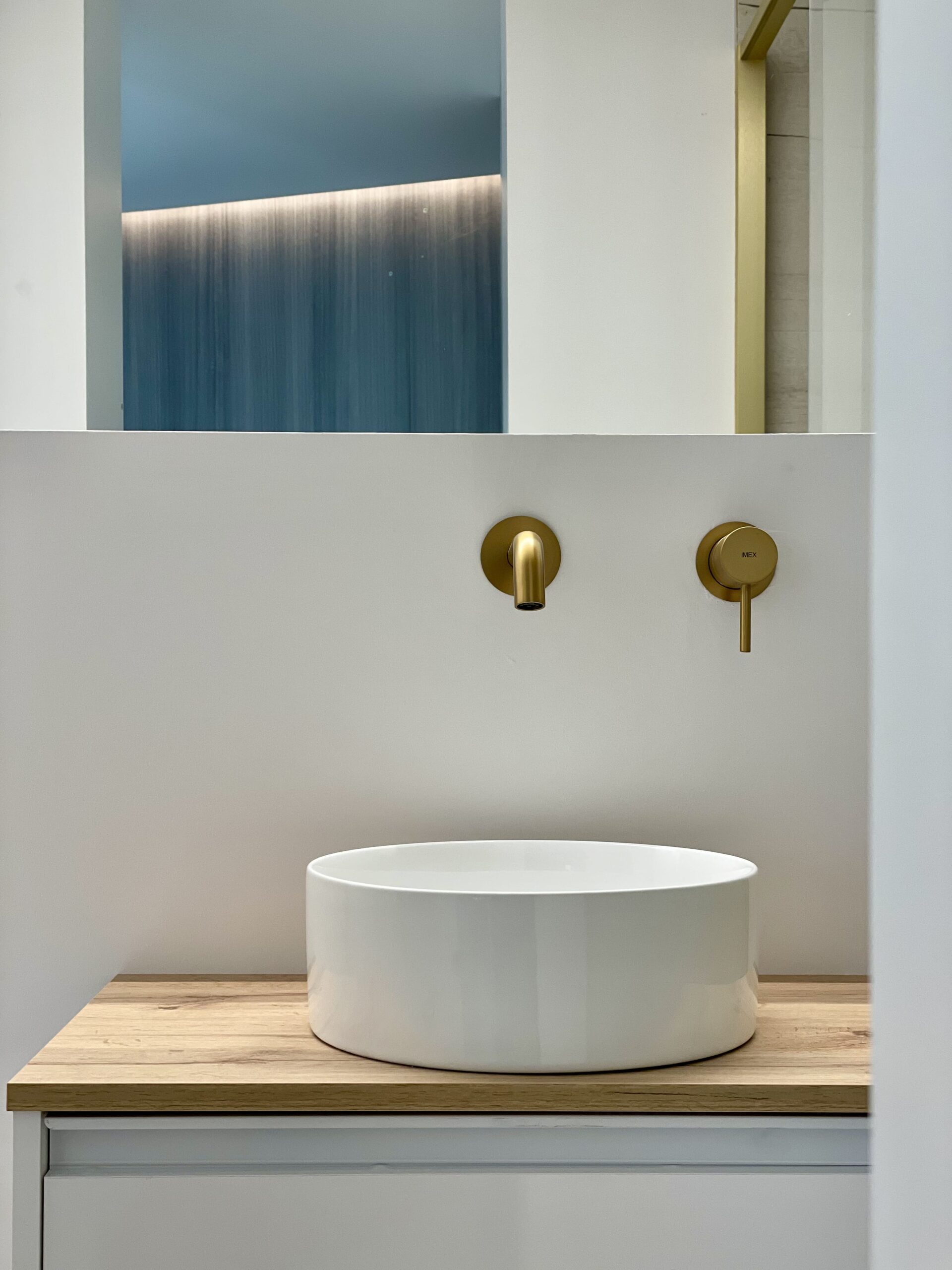 Lavabo redondo con grifo de pared dorado