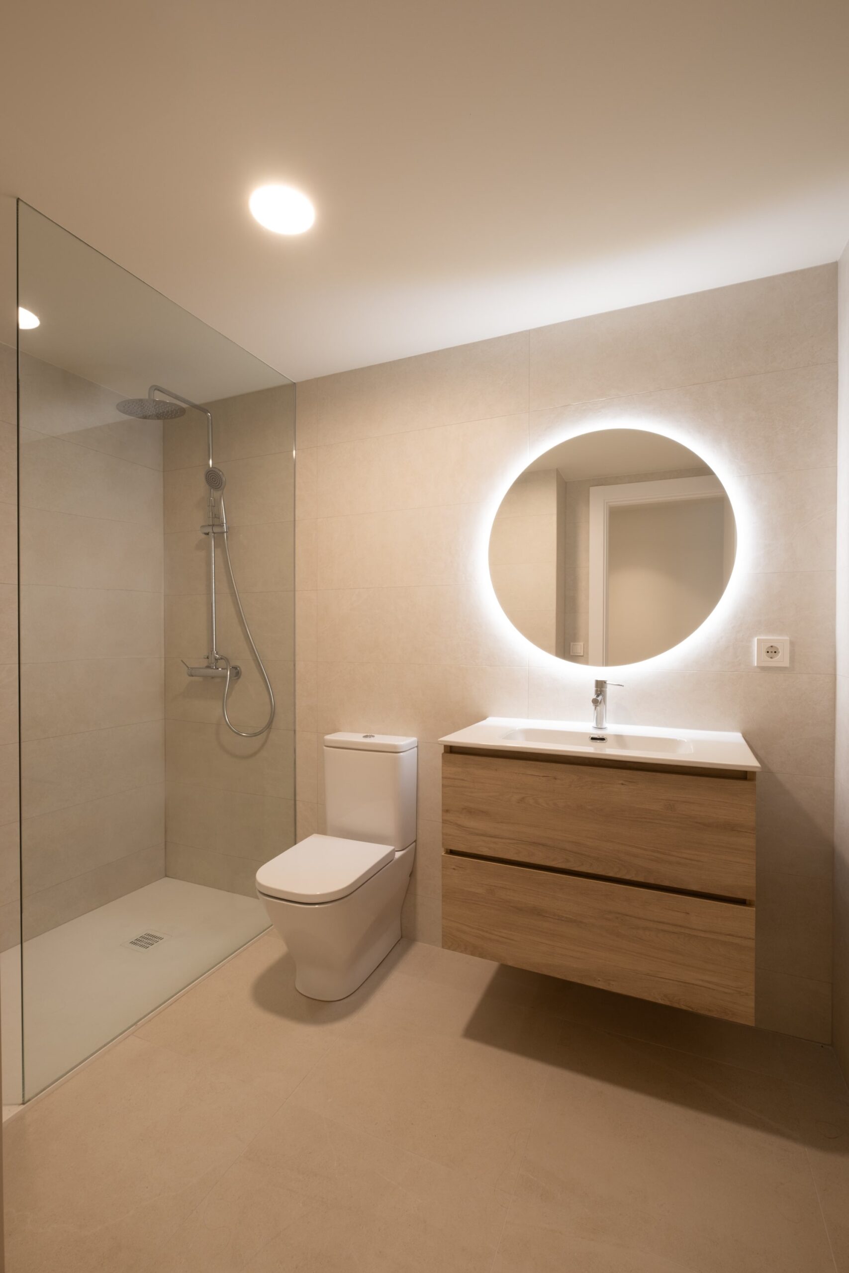 Baño con espejo redondo retroiluminado y ducha