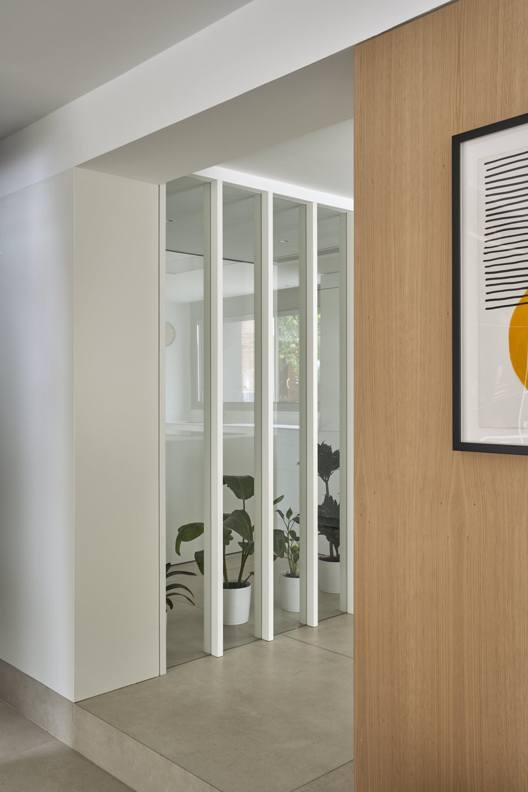 Celosía blanca de lamas verticales junto al panel de madera