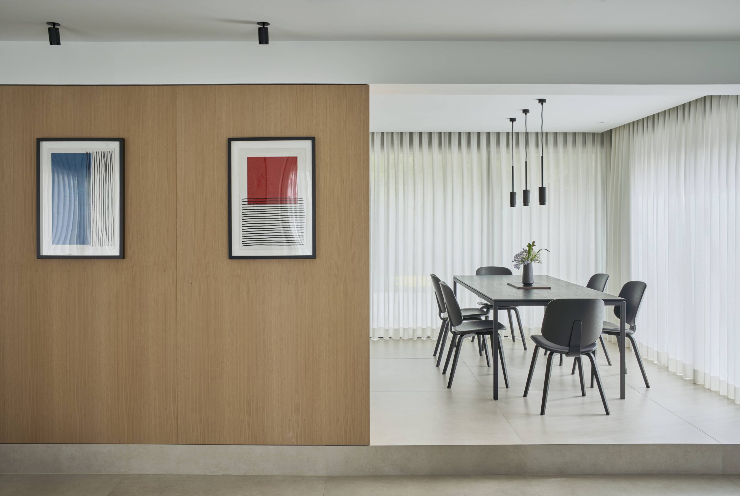 Comedor con lámparas colgantes negras junto al panel de madera