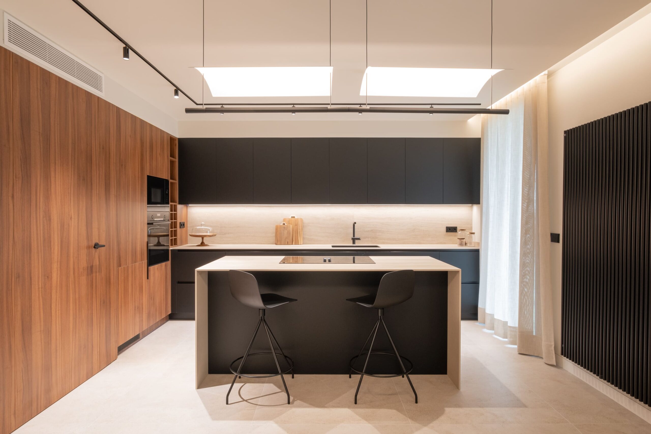 Cocina con isla, frentes negros y pared de nogal