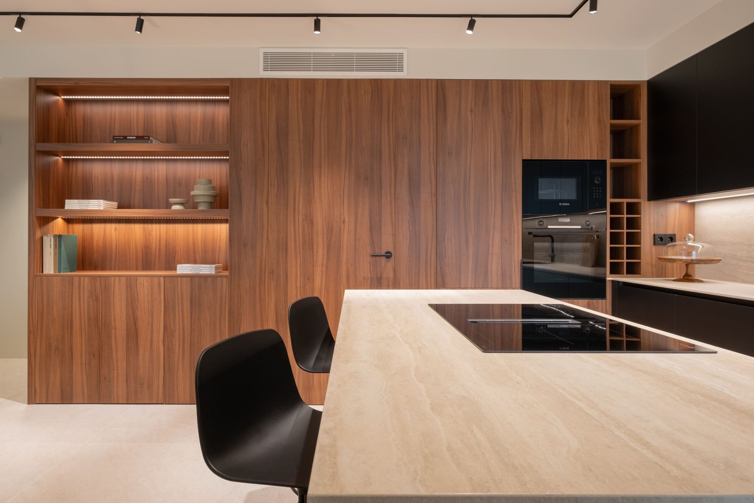 Isla con placa de inducción y taburetes negros en una vivienda reformada