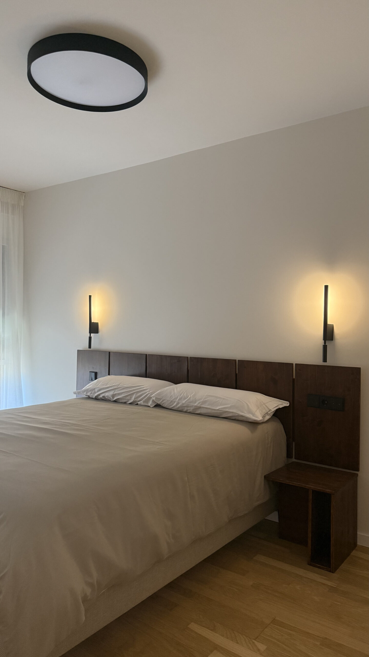 Dormitorio con cabecero de madera y apliques de pared