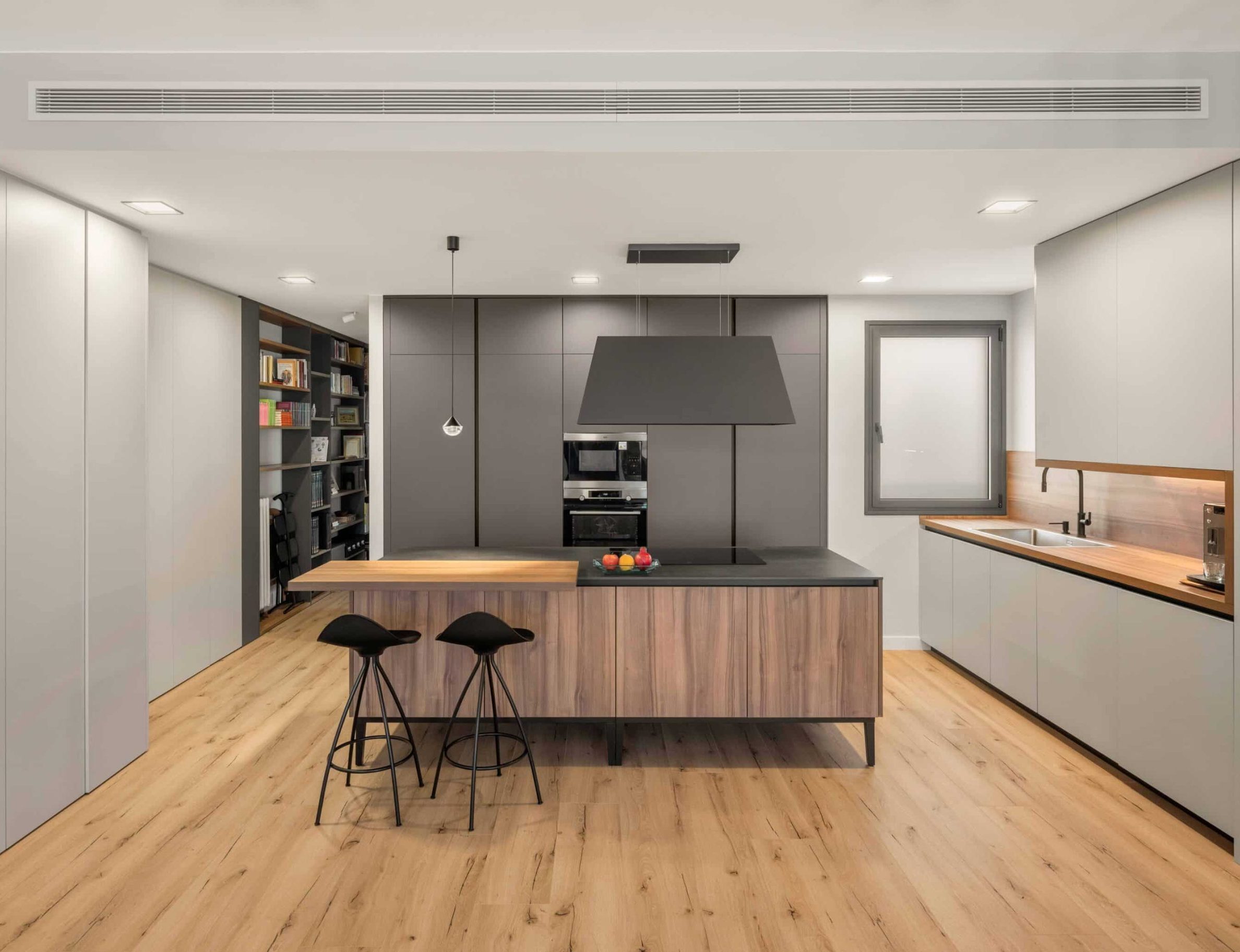 Cocina con isla de madera y taburetes negros