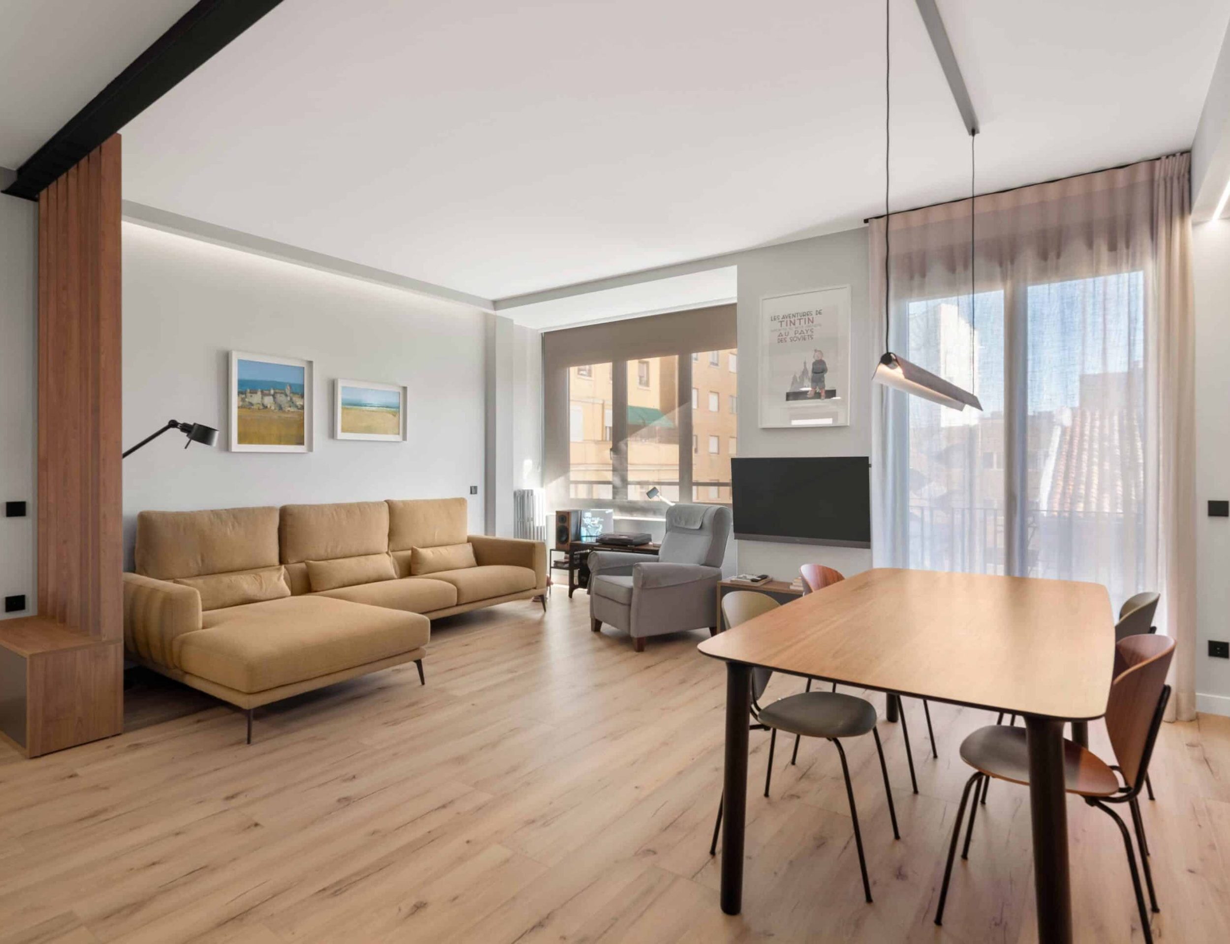 Salón comedor con mesa de madera y sofá mostaza tras la reforma