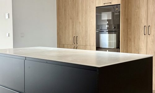 Cocina con isla negra y columnas de madera, proyecto JB04