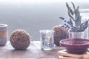 mesa con elementos decorativos naturaless velas y cestas en salon acogedor con sofa y cojines