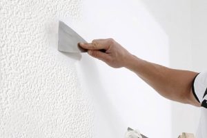 Persona rascando el gotele de una pared