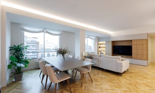 Salón comedor con suelo de espiga y sofá blanco en un piso reformado