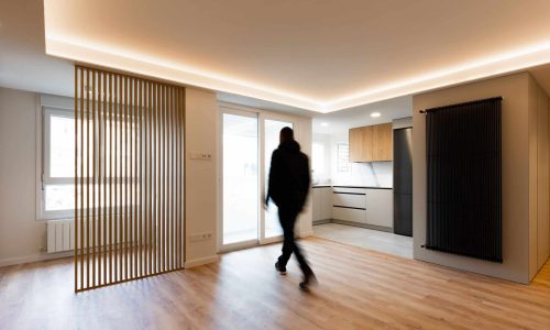 Salón con celosía de listones de madera y techo con luz indirecta