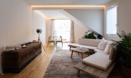Salón en tonos blancos bajo la cubierta inclinada, proyecto JM 7