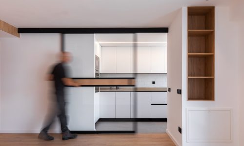 Vivienda reformada con cocina acristalada y estantería de madera